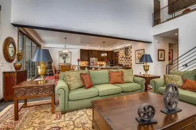 a living room with green couches and a table at Allure at Schaffer's Mill by Tahoe Getaways - 4BR Pet-Friendly Home w Private Hot Tub & Air Conditioning! in Truckee
