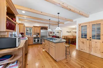 a large kitchen with wooden cabinets and a table at Fox Crossing at Tahoe Donner by Tahoe Getaways - 3BR Vacation Rental w Forested Views & HOA Amenities! in Truckee