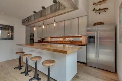 a kitchen with a counter with stools and a refrigerator at Mod Haus by Tahoe Getaways - Mountain Modern West Shore Home w Private Beach and Pier, Near Skiing in Homewood