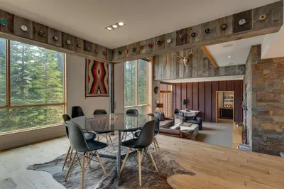a living room with a glass table and chairs at Mod Haus by Tahoe Getaways - Mountain Modern West Shore Home w Private Beach and Pier, Near Skiing in Homewood