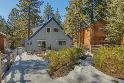 a house in the snow in front of a log cabin at Moon Dune Chalet by Tahoe Getaways - Remodeled 3 BR Cabin plus Loft w Fenced Yard & Walk to Beach or Dining in Tahoe Vista