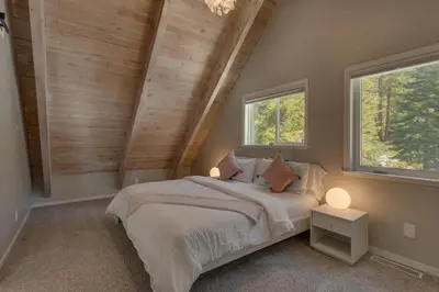 a bedroom with a bed and two windows at Moon Dune Chalet by Tahoe Getaways - Remodeled 3 BR Cabin plus Loft w Fenced Yard & Walk to Beach or Dining in Tahoe Vista