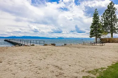a beach with a picnic table and a pier at Nightingale Retreat by Tahoe Getaways - 3BR, Close to Tahoe City, Walk to Bike Path & Private Beach Access in Tahoe City