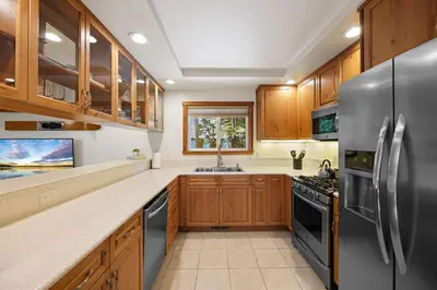 a kitchen with wooden cabinets and a stainless steel refrigerator at Sunlit Pines by Tahoe Getaways - 2BR in Tahoe Park w Hot Tub, Fenced Yard & Pet Friendly! in Tahoe City