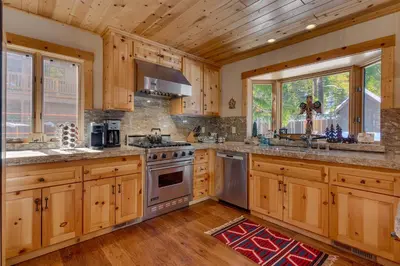 a kitchen with wooden cabinets and stainless steel appliances at Tippy Canoe by Tahoe Getaways - 4BR West Shore w Private Hot Tub,, Sauna, EV & Walking Distance to Trailhead in Tahoma