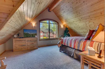 a bedroom with a large bed and a window at Tippy Canoe by Tahoe Getaways - 4BR West Shore w Private Hot Tub,, Sauna, EV & Walking Distance to Trailhead in Tahoma