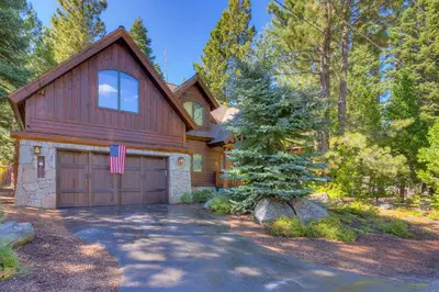 a wooden house with a garage and a driveway at Tippy Canoe by Tahoe Getaways - 4BR West Shore w Private Hot Tub,, Sauna, EV & Walking Distance to Trailhead in Tahoma