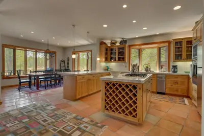 a large kitchen with wooden cabinets and a table at Tranquil Retreat by Tahoe Getaways - 3BR Pet-Friendly Home w Private Hot Tub, Views & HOA Amenities in Truckee