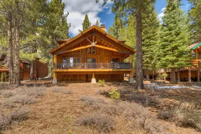 a large log cabin in the woods with trees at Tranquil Retreat by Tahoe Getaways - 3BR Pet-Friendly Home w Private Hot Tub, Views & HOA Amenities in Truckee