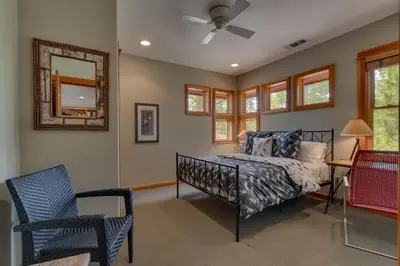 a bedroom with a bed and a mirror and a chair at Tranquil Retreat by Tahoe Getaways - 3BR Pet-Friendly Home w Private Hot Tub, Views & HOA Amenities in Truckee