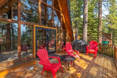 four red chairs and a table on a deck at Ember Ridge Retreat by Tahoe Getaways - 3BR Pet-Friendly Carnelian Bay Rental w Fenced Yard, Ping Pong, Hot Tub, Near Northstar in Carnelian Bay
