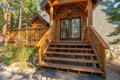 a cabin with a staircase leading to the front door at Ember Ridge Retreat by Tahoe Getaways - 3BR Pet-Friendly Carnelian Bay Rental w Fenced Yard, Ping Pong, Hot Tub, Near Northstar in Carnelian Bay