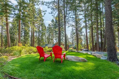 two red chairs sitting in the grass in a park at Ember Ridge Retreat by Tahoe Getaways - 3BR Pet-Friendly Carnelian Bay Rental w Fenced Yard, Ping Pong, Hot Tub, Near Northstar in Carnelian Bay