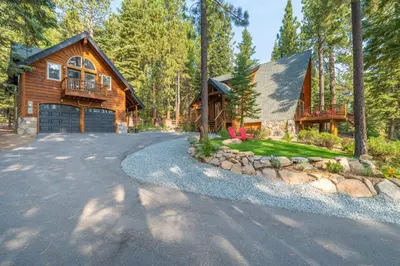 a house in the woods with a driveway at Ember Ridge Retreat by Tahoe Getaways - 3BR Pet-Friendly Carnelian Bay Rental w Fenced Yard, Ping Pong, Hot Tub, Near Northstar in Carnelian Bay