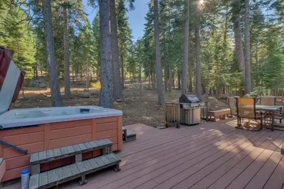 a deck with a jacuzzi tub and a grill at Fireside Lodge at Northstar By Tahoe Getaways - 4BR w Hot Tub, HOA & Ski Shuttle in Truckee