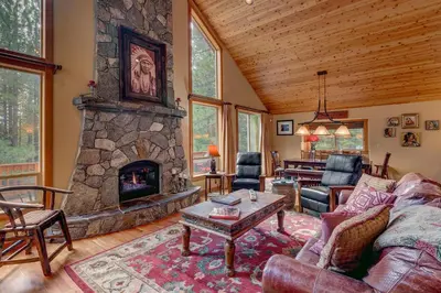 a living room with a large stone fireplace at High Country Lodge by Tahoe Getaways - Tahoe Donner 4BR w Hot Tub, Air Conditioning, EV, HOA, Shuffleboard and Horse Shoe Pit in Truckee