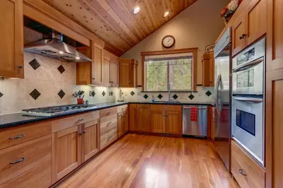a kitchen with wooden cabinets and a wooden floor at High Country Lodge by Tahoe Getaways - Tahoe Donner 4BR w Hot Tub, Air Conditioning, EV, HOA, Shuffleboard and Horse Shoe Pit in Truckee