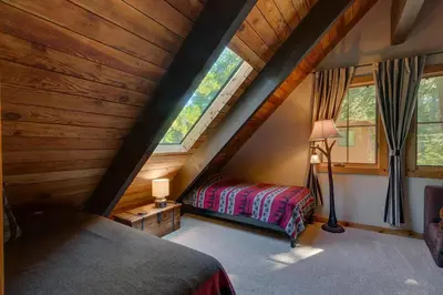 a attic bedroom with two beds and two windows at Lazy Bear in Tahoe City