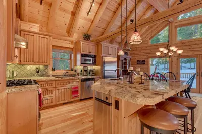a kitchen with a large island in a log cabin at Lodgepole Retreat - A Gorgeous Classic 3BR Log Cabin with Private Hot Tub in Truckee