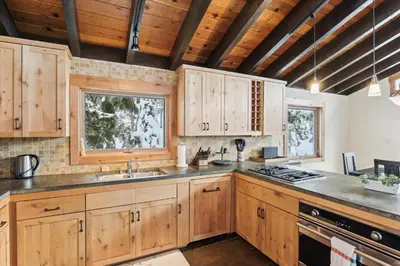 a kitchen with wooden cabinets and a stove top oven at Mariposa Heights at Alpine - Ski Shuttle to Slopes- Fireplace- Forest Views in Alpine Meadows