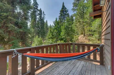 a hammock on a wooden deck with trees at Mountain Escape at North Shore - Upscale 4BR Easy Walk to Lake & Private Hot Tub! in Carnelian Bay
