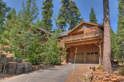 a log home with a porch and a driveway at Mountain Escape at North Shore - Upscale 4BR Easy Walk to Lake & Private Hot Tub! in Carnelian Bay