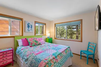 a bedroom with a bed and a blue chair at Mosaic Magic at Northstar - Luxury 4BR with Private Hot Tub and Free Ski Shuttle in Truckee