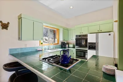 a kitchen with green cabinets and a tea kettle on the stove at Mosaic Magic at Northstar - Luxury 4BR with Private Hot Tub and Free Ski Shuttle in Truckee