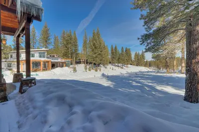 a snow covered yard in front of a house at Mountain Majesty at Grays Crossing - Luxury 4BR 4BA w Private Hot Tub in Truckee
