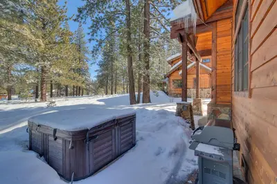 a snow covered shed next to a log cabin at Mountain Majesty at Grays Crossing - Luxury 4BR 4BA w Private Hot Tub in Truckee