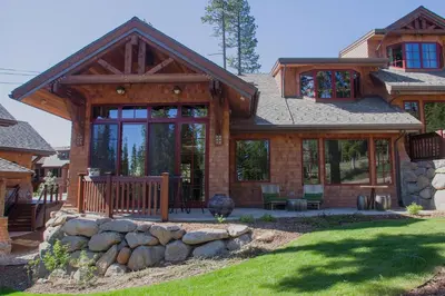 a log home with a porch and a stone wall at Mountainside by Tahoe Getaways - Luxury Pet-Friendly Northstar Ski-in Ski-Out - Swimming Pool and Gym! in Truckee