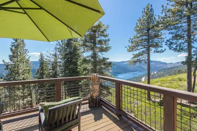 a deck with two chairs and an umbrella at Overlook Lake View Lodge by Tahoe Getaways- Dog Friendly, HOA, Sauna, Hot Tub, Views of Donner Lake in Truckee