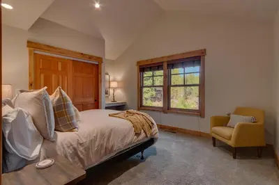 a bedroom with a bed and a chair and a window at Pine Meadow at Gray's Crossing - 4BR w Two Master Suites in Truckee