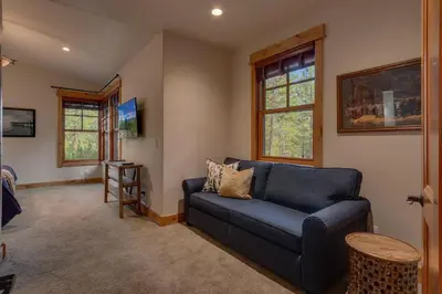 a living room with a blue couch and windows at Pine Meadow at Gray's Crossing - 4BR w Two Master Suites in Truckee