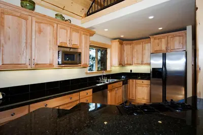 a kitchen with wooden cabinets and a stainless steel refrigerator at Red Cedar on North Shore - Beautiful 3BR w Gorgeous Furnishings in Tahoe City in Tahoe City