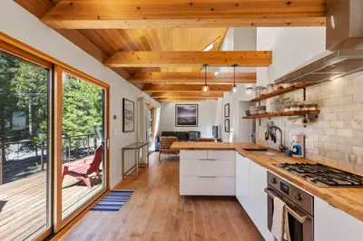 a kitchen with white cabinets and a large window at Wildwood - Modern 2 BR with Private Hot tub Walk to North Tahoe Regional Park in Tahoe Vista