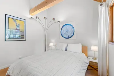 a white bedroom with a bed and a lamp at Wildwood - Modern 2 BR with Private Hot tub Walk to North Tahoe Regional Park in Tahoe Vista