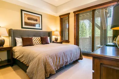 a bedroom with a bed and a desk and windows at Village Walk - Private Hot Tub, HOA Amenities, Pet Friendly, Walk to Lifts! in Truckee