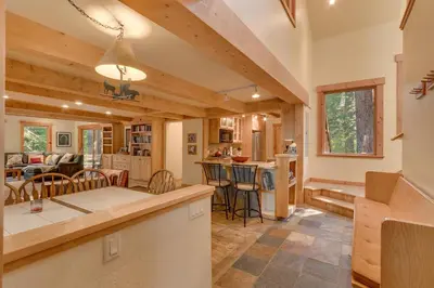 a kitchen and living room in a log home at West Pine Cabin on the West Shore by Tahoe Getaways - 2 BR w 2 Bonus Rooms, Hot Tub, Pool Table & Pet Friendly in Tahoe City