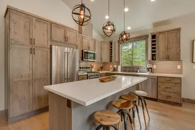 a kitchen with wooden cabinets and a large island with stools at Sunrise Abode at Tahoe Donner - Luxurious New Build, Soaking Tub, HOA Amenities in Truckee