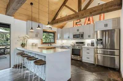 a kitchen with white cabinets and a large island with stools at Timber Grove at Tahoe Park - Gorgeous 4BR Cabin - Tahoe Park HOA, Pets OK, Near Skiing in Tahoe City