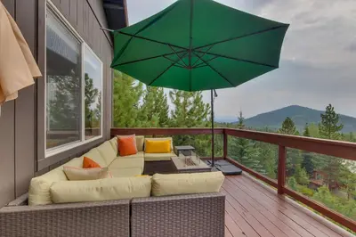 a patio with a couch and a large green umbrella at Treetop at Tahoe Donner - Pet Friendly 4BR w Gym and Pool Access in Truckee