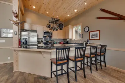 a kitchen with a bar with chairs and a counter top at Treetop at Tahoe Donner - Pet Friendly 4BR w Gym and Pool Access in Truckee