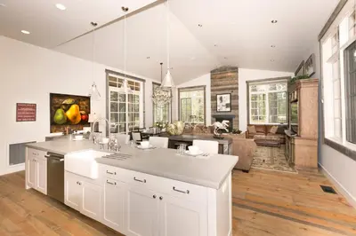 a kitchen with white cabinets and a living room at First Light Farmhouse- Hot Tub- Gourmet Kitchen- Premier Neighborhood in Truckee