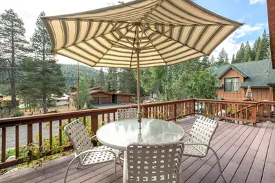 a table and chairs with an umbrella on a deck at Victory Place at Palisades - Stunning 5 BR with Private Hot Tub and Pool Table in Olympic Valley