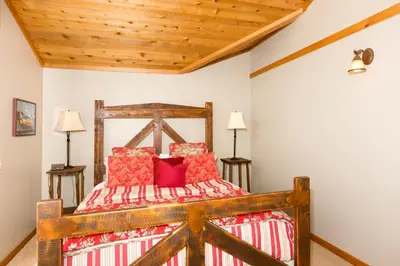 a bedroom with a wooden bed with red pillows at Victory Place at Palisades - Stunning 5 BR with Private Hot Tub and Pool Table in Olympic Valley