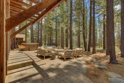 a patio with tables and chairs in the woods at Truckee Treasure at Grays Crossing by Tahoe Getaways - Relaxing Home w Private Hot Tub, Dogs Welcome! in Truckee