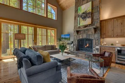 a living room with couches and a stone fireplace at Truckee Treasure at Grays Crossing by Tahoe Getaways - Relaxing Home w Private Hot Tub, Dogs Welcome! in Truckee
