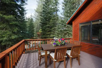a wooden deck with a wooden table and chairs at St Bernard at Tahoe Donner Remodeled 3BR - Private Hot Tub and Gym and Pool Access in Truckee