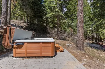 a hot tub sitting on a patio in the woods at Trailside - Alpine Meadows 6 Bedroom with Private Hot tub in Alpine Meadows